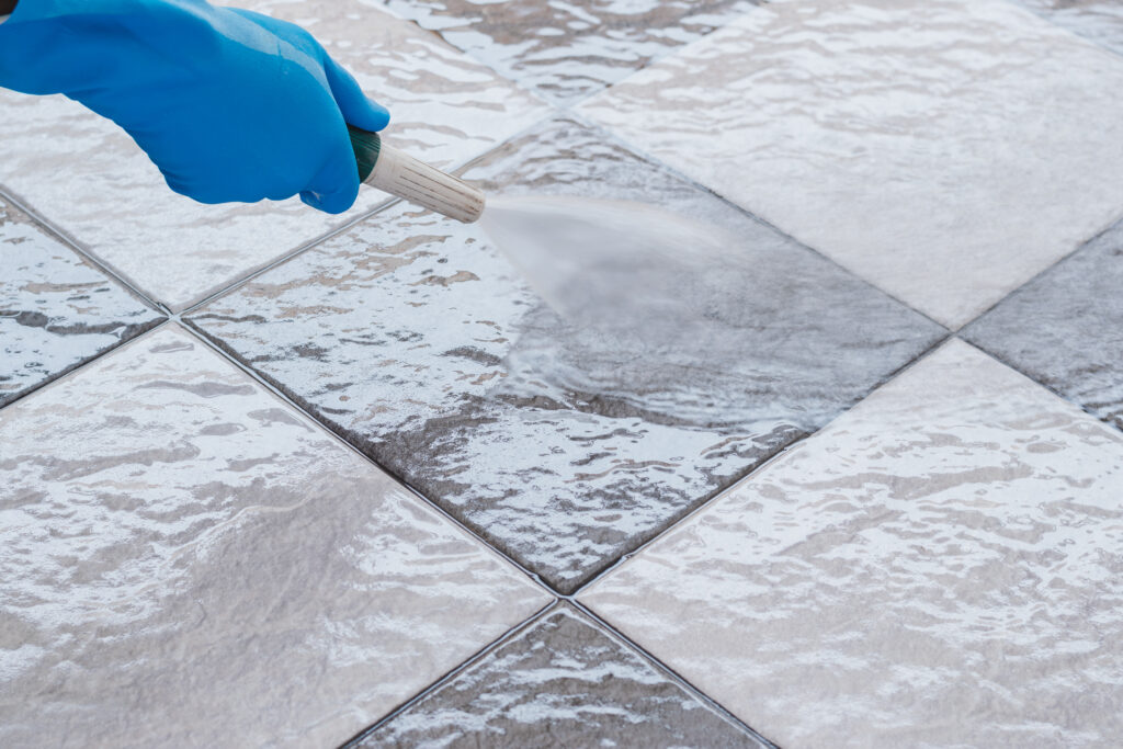 Cleaning the tile floor. man wearing blue rubber gloves using a hose to cleaning the tile floor.