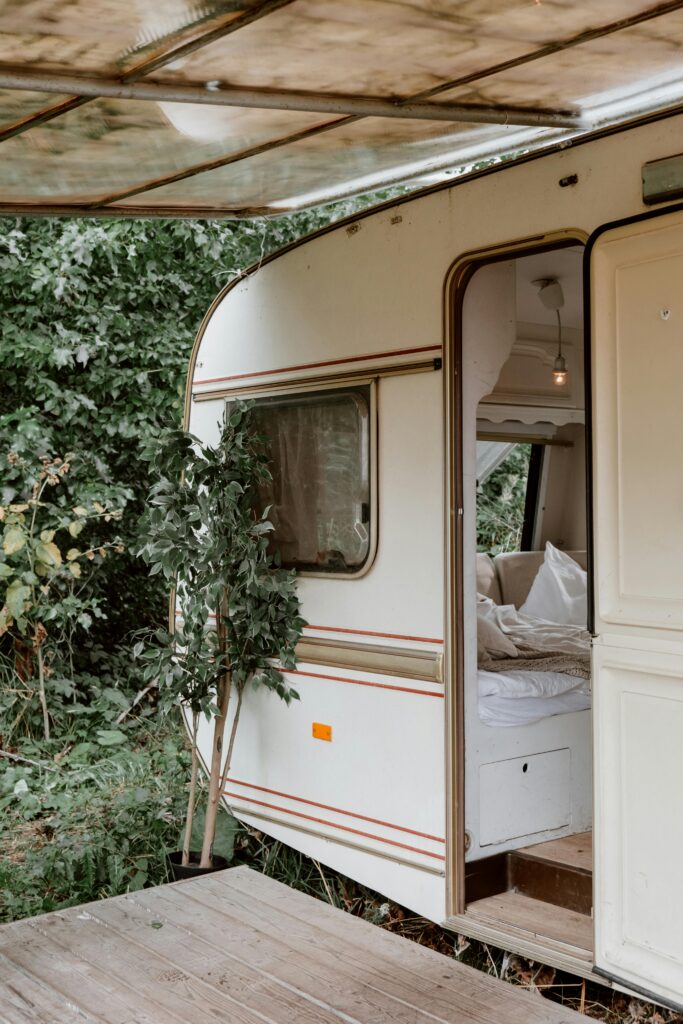 A cozy camper trailer surrounded by lush greenery, offering an inviting retreat in nature.